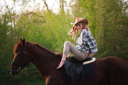 Beautiful girl in a hat riding a horse in countrysideの写真素材