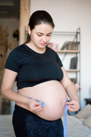 Pregnant woman measuring her belly. Healthy pregnancy. Health pregnancy lifestyle.の写真素材