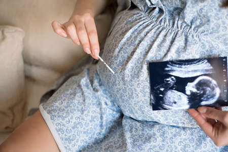 Pregnant woman looking at baby ultrasound scan.