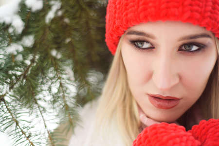 Young girl in a red hat and mittens outdoors in winter.の写真素材