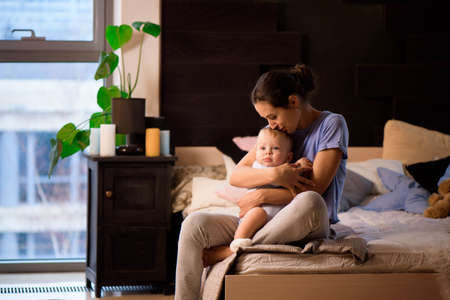 Mother and her son child girl playing and hugging on the bed.