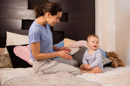 Mother with her cute little son playing on bed.