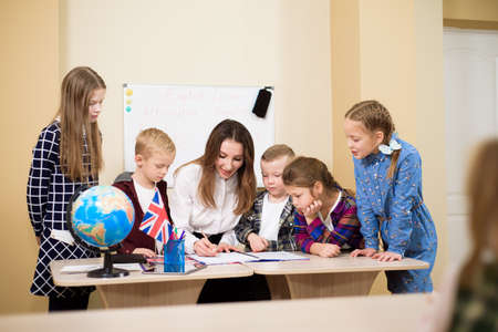 Group Of Primary Schoolchildren And Teacher Working At Desks In Classroomの写真素材