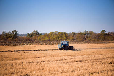 the tractor plows the field in autumnの写真素材