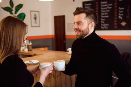 Beautiful Woman And Handsome Man Drinking Coffee While Spending Time In Coffee Shop.の写真素材
