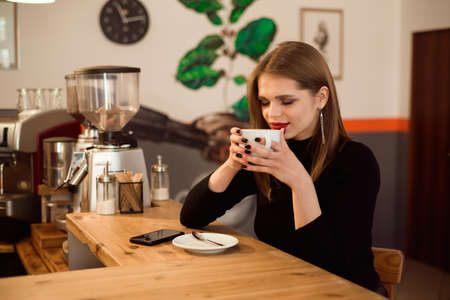 portrait of young woman drinking coffee in cafeの写真素材