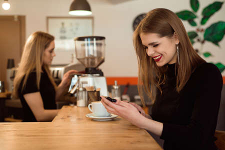 Smiling woman in a good mood enjoy cup of coffee sitting in a cafe.の写真素材