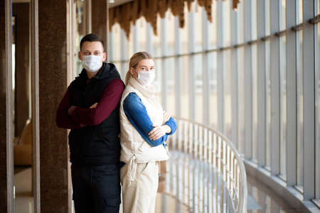 Young couple wearing a mask in an airport lounge. Coronavirus influenza virus travel concept.の写真素材