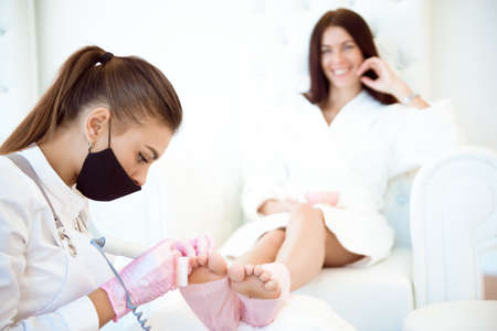 Pedicurists hands in protective rubber gloves applying nail polish to the toenails