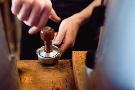 Barista presses ground coffee using tamper in a coffe shopの写真素材