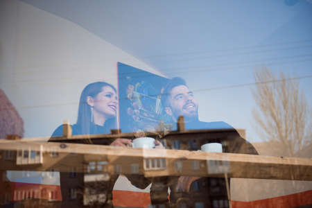 Good looking couple laughing and having a good time on a date in a coffee shopの写真素材