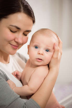 Close up portrait of beautiful young mother girl kissing her newborn baby