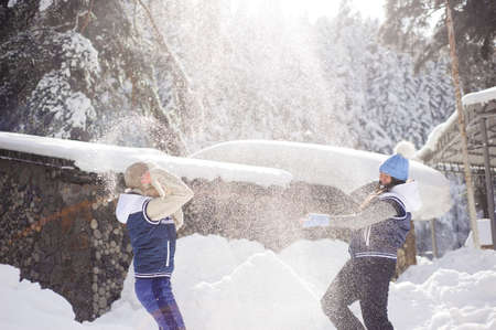 Two girlfriends have fun and enjoy fresh snow on a beautiful winter dayの写真素材