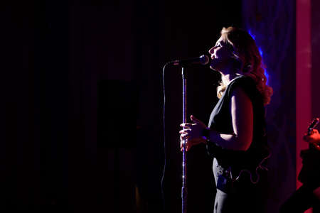 Female singer, performing her vocal sound. With lens flare and spotlight.の写真素材