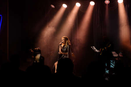 Singer with her band performing on stage. Concert. View from the auditorium.