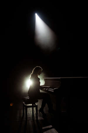 Female keyboards player on stage during concert, backlightの写真素材