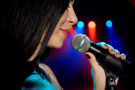 Singer with microphone on the colorful light stage background