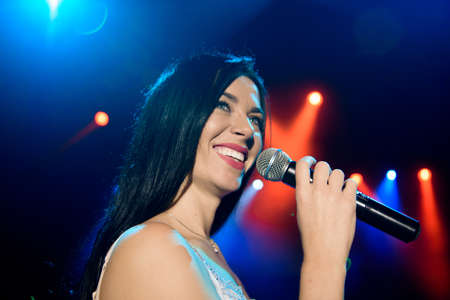 Singer with microphone on the colorful light stage backgroundの写真素材