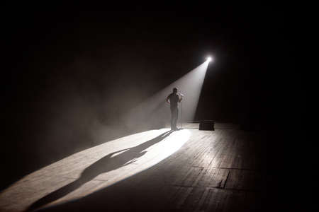 Stand up comedian on stage in the beam of light.の写真素材