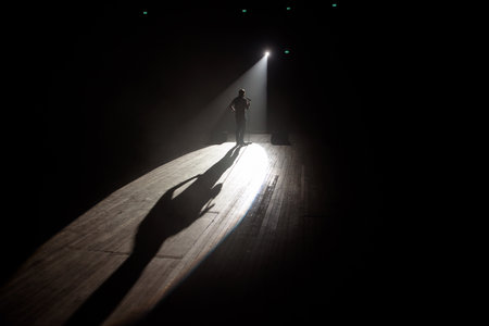 Stand up comedian on stage in the beam of light.