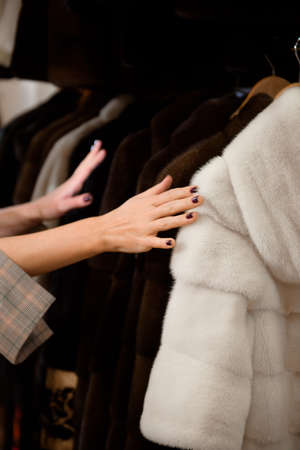 Attractive woman in fur coat shop with a fur coats on the hangerの写真素材