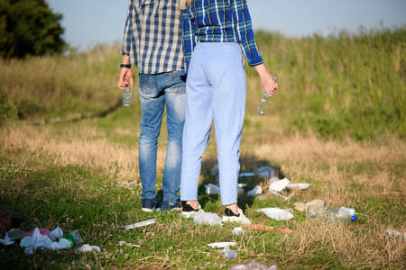Trash on the Beach. Young couple resting on the beach next to a pile of trash. Human and nature conceptの写真素材