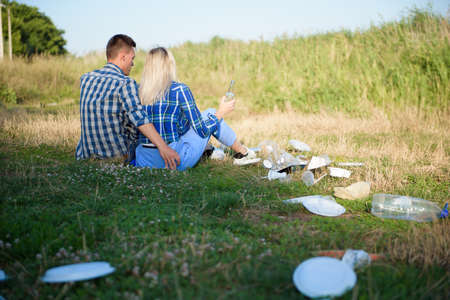 Trash on the Beach. Young couple resting on the beach next to a pile of trash. Human and nature conceptの写真素材