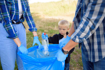 volunteering, charity, people and ecology concept, volunteers using garbage bag while collecting...