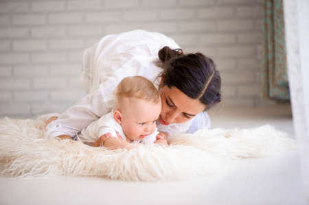 Mother and child in a white room. Mom and baby boy in diaper plaの写真素材