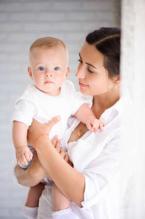Mother and child in a white room. Mom and baby boy in diaper plaの写真素材