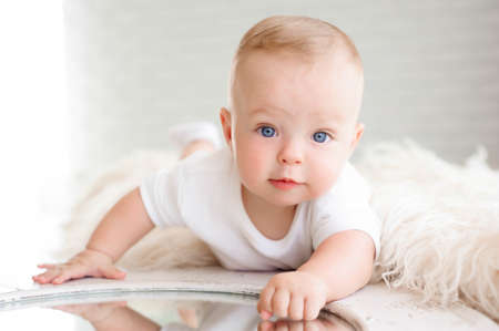 Little boy of 7 months plays on the white carpet in the bedroomの写真素材