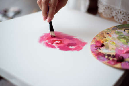 Woman artist drawing her picture on canvas with oil colors at homeの写真素材