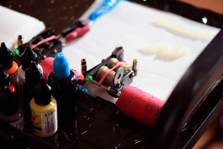 Tattoo artist at work. Close up. Man creating picture on hand with it in salonの写真素材