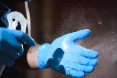 Tatto salon closeup. A man wearing protective gloves disinfects his hands before work.の写真素材