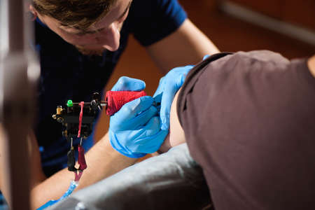 Tattoo artist creating a tattoo on a mans armの写真素材