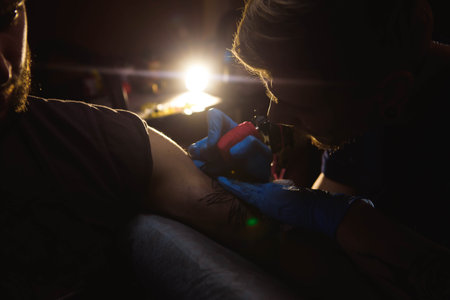 Professional tattoo artist makes a tattoo on a mans hand.の写真素材