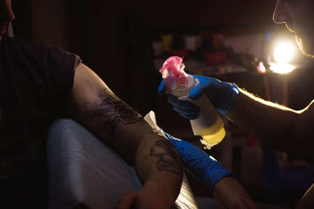 Tattoo artist makes a tattoo on a mans hand. Man creating picture on hand with it in salonの写真素材