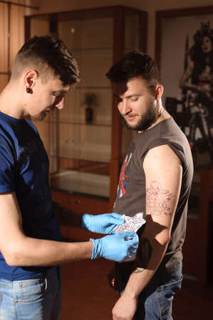 Tattoo artist at work. Man creating picture on hand with it in salon.の写真素材
