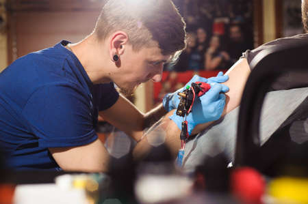 Tattoo artist creating a tattoo on a mans armの写真素材