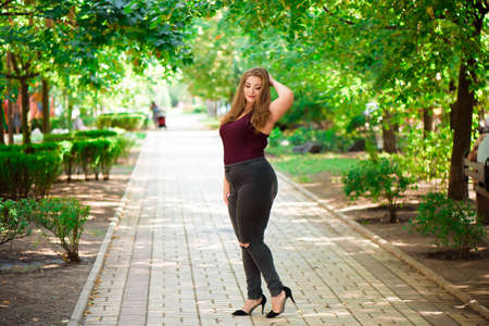 Plus size fashion model in casual clothes, overweight female body in a park outdoorsの写真素材