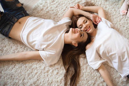 Happy girlfriends lying on back top view sisters.の写真素材