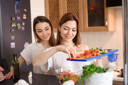 Smiling sisters preparing dinner together in the kitchen.の写真素材