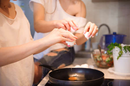 Friends prepearing brekfast and having meal in kitchen together.の写真素材