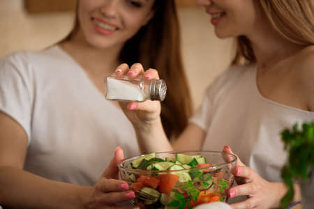 Smiling sisters preparing dinner together in the kitchen.の写真素材