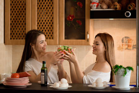 Smiling sisters preparing dinner together in the kitchen.の写真素材