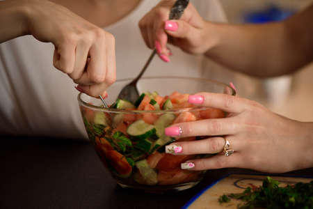 Young sisters making vegetable salad at home.の写真素材