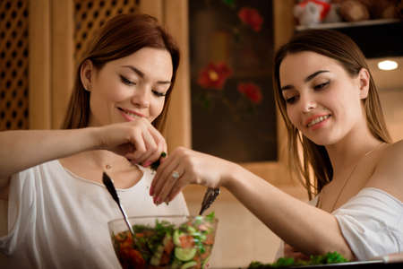 Young sisters making vegetable salad at home.の写真素材