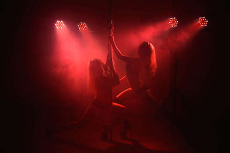 Two young girls doing acrobatic tricks with a pole.の写真素材