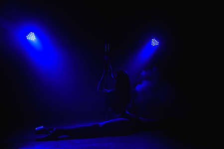 Beautiful slim girl with pylon. Female pole dancer woman dancing on a pole on a black background.の写真素材