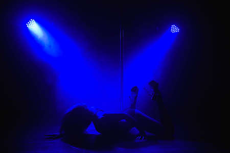 Beautiful slim girl with pylon. Female pole dancer woman dancing on a pole on a black background.の写真素材